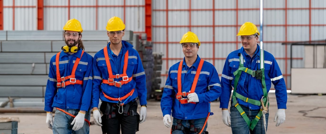 A group of factory workers wearing hard hats and lanyards